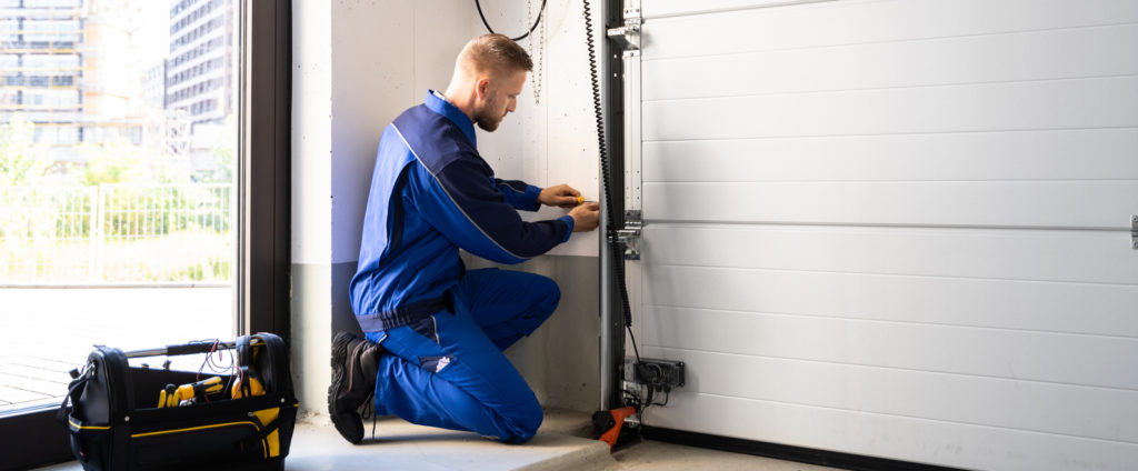 Man tuning up garage door rail. What is Included in a Garage Door Tune-Up