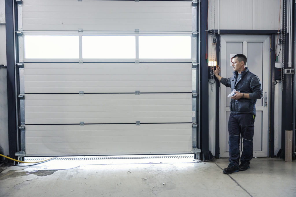 homeowner standing by garage door, wondering why are garage door springs dangerous