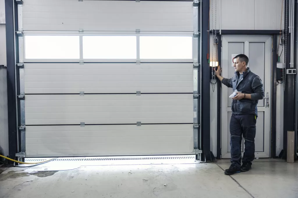 homeowner standing by garage door, wondering why are garage door springs dangerous