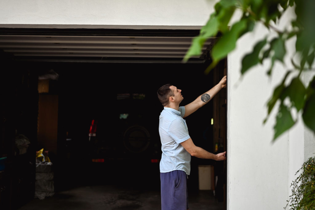 man inspecting broken door, wondering about garage door replacement cost